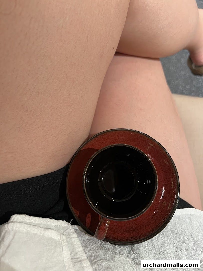 A close-up shot of a person's legs with a coffee cup and saucer.