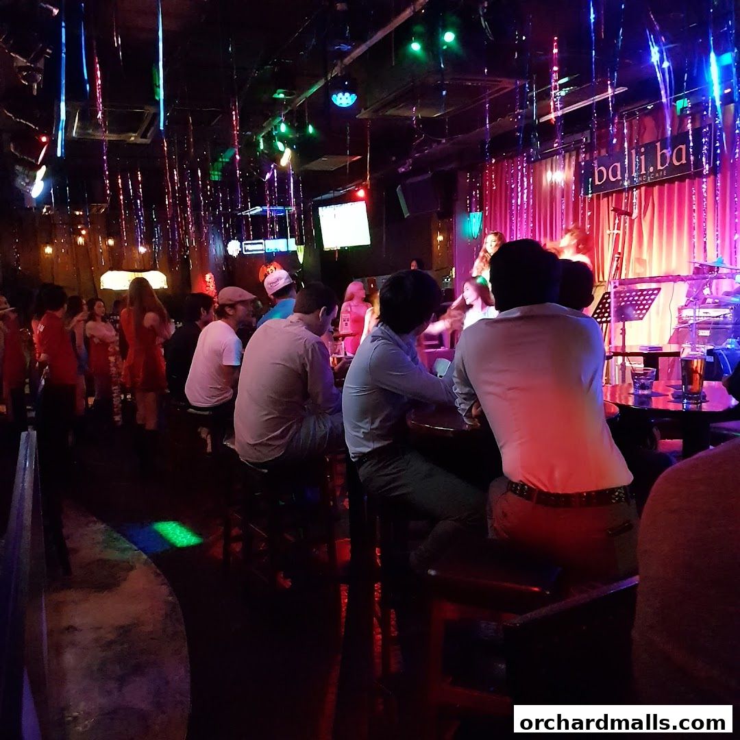 People enjoying a live band performance at a bar with colorful lighting.