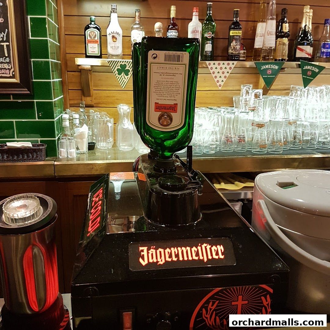 A Jägermeister dispenser and bottles of alcohol on a bar counter.