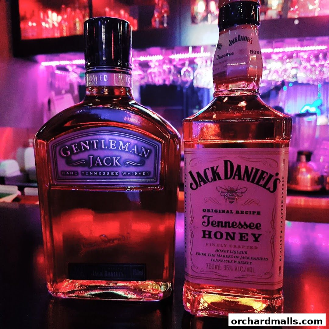 Two bottles of whiskey, Gentleman Jack and Jack Daniel's Tennessee Honey, displayed on a bar.