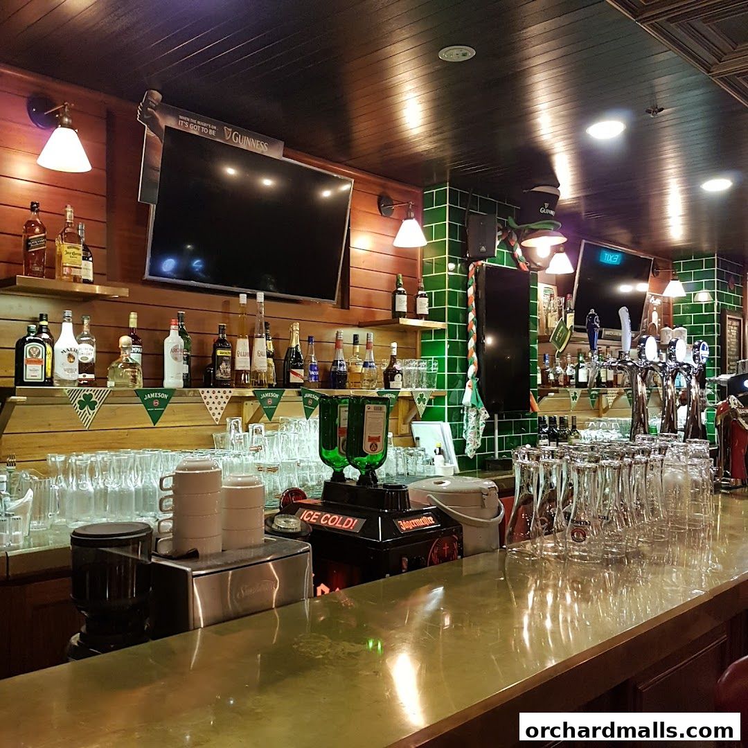 A well-stocked bar with bottles, glasses, and beer taps, featuring Irish-themed decor.