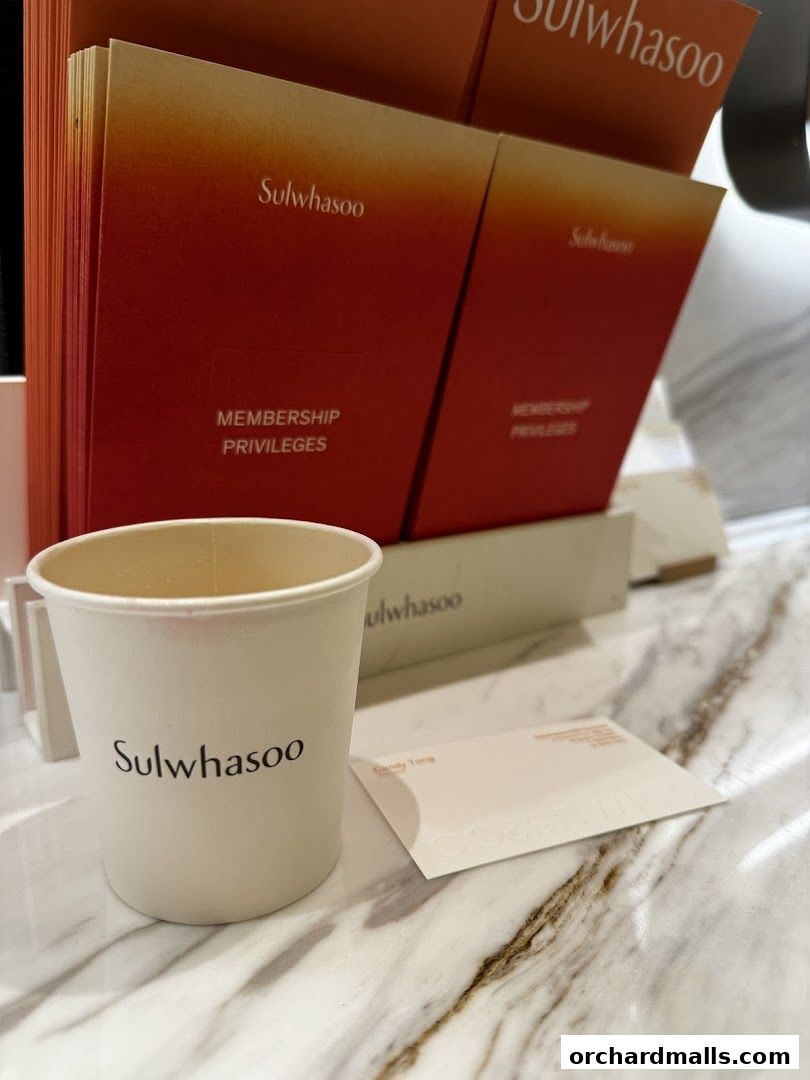 A Sulwhasoo branded cup sits on a marble counter with membership privilege brochures.