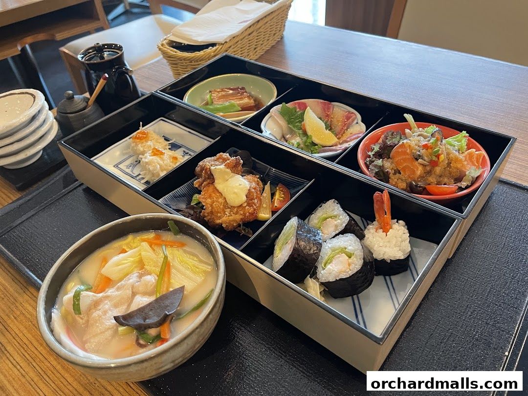 A bento box meal with various Japanese dishes and a bowl of soup.