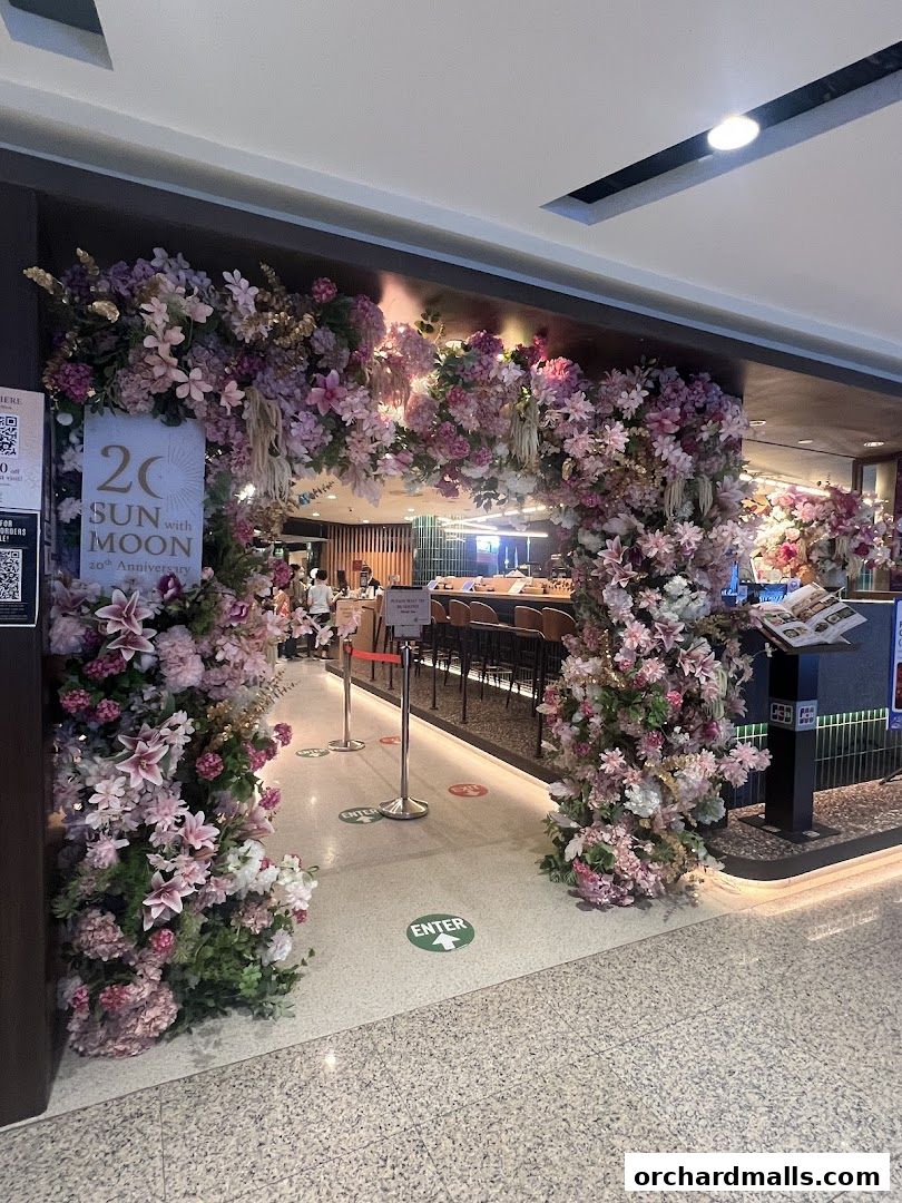 Entrance to SUN with MOON Japanese Dining Cafe, adorned with floral decorations and anniversary signage.
