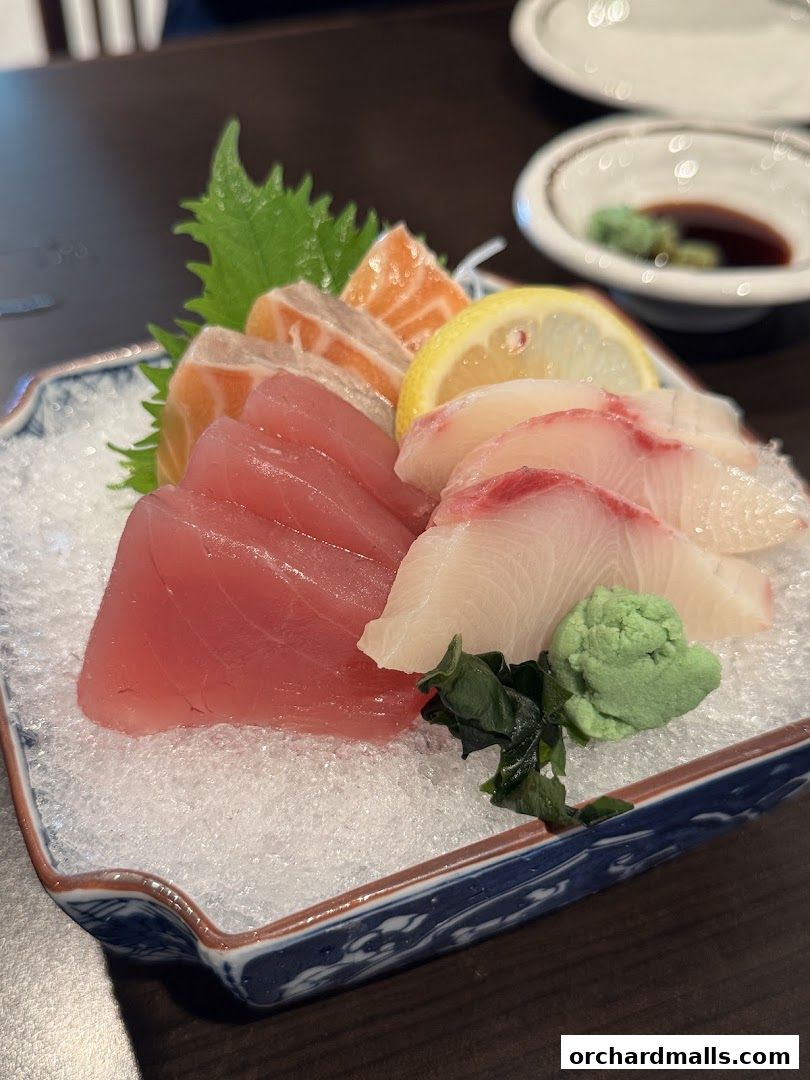 A close-up of a sashimi platter with tuna, salmon, and white fish, served with wasabi and soy sauce.