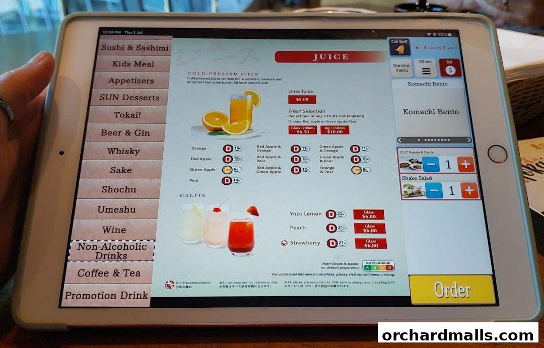 A tablet displays a digital menu for SUN with MOON Japanese Dining Cafe, showing juices and bento options.