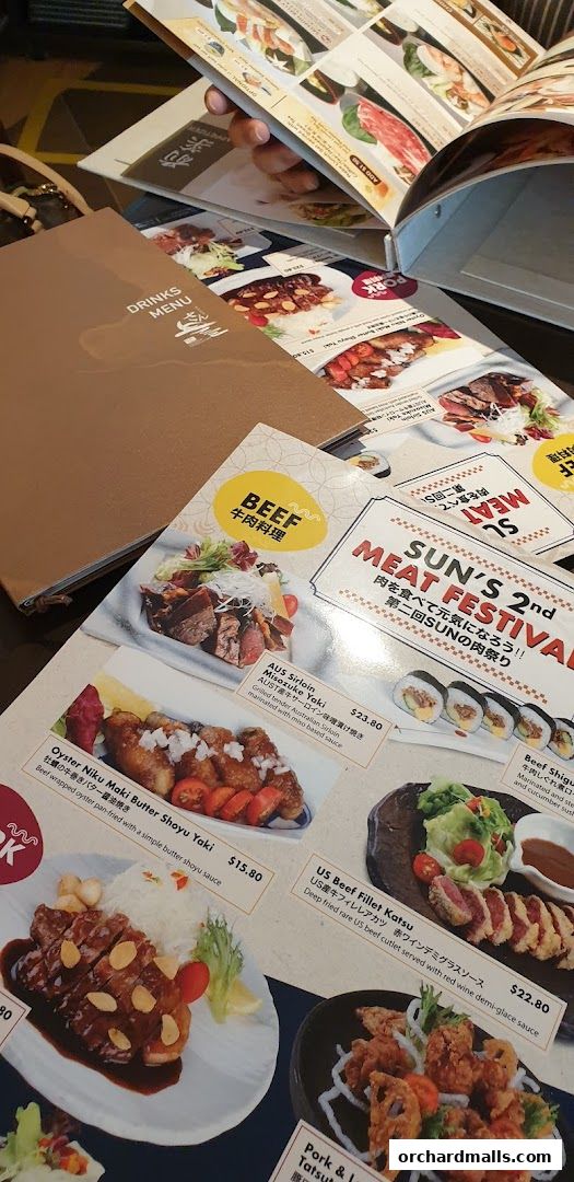 A close-up view of a Japanese dining menu featuring various meat dishes and drinks.