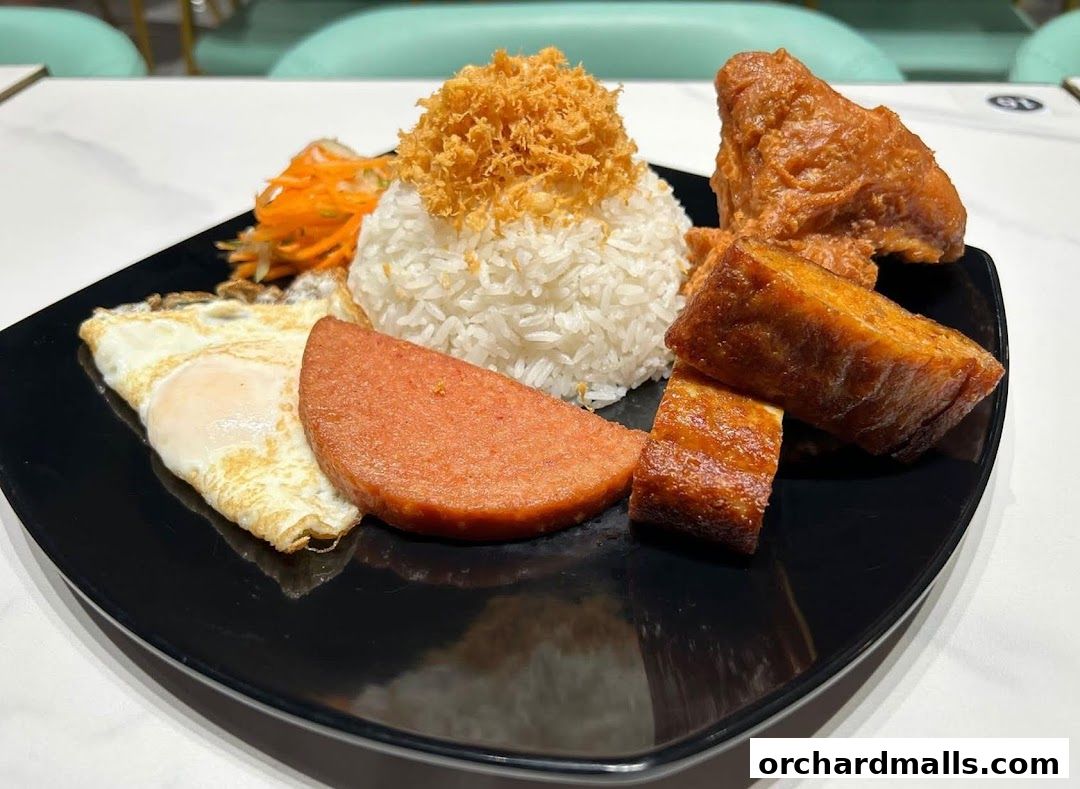A black plate filled with a hearty meal including rice, fried egg, spam, fried chicken, and fried tofu.