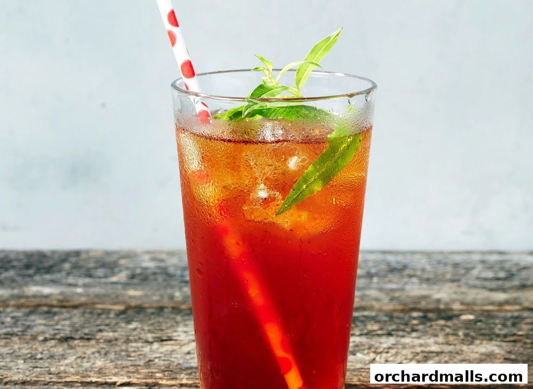 A tall glass of iced tea with a straw and fresh mint leaves.