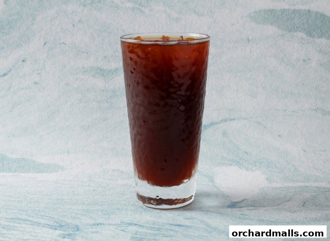 A tall glass filled with iced coffee or a dark beverage.