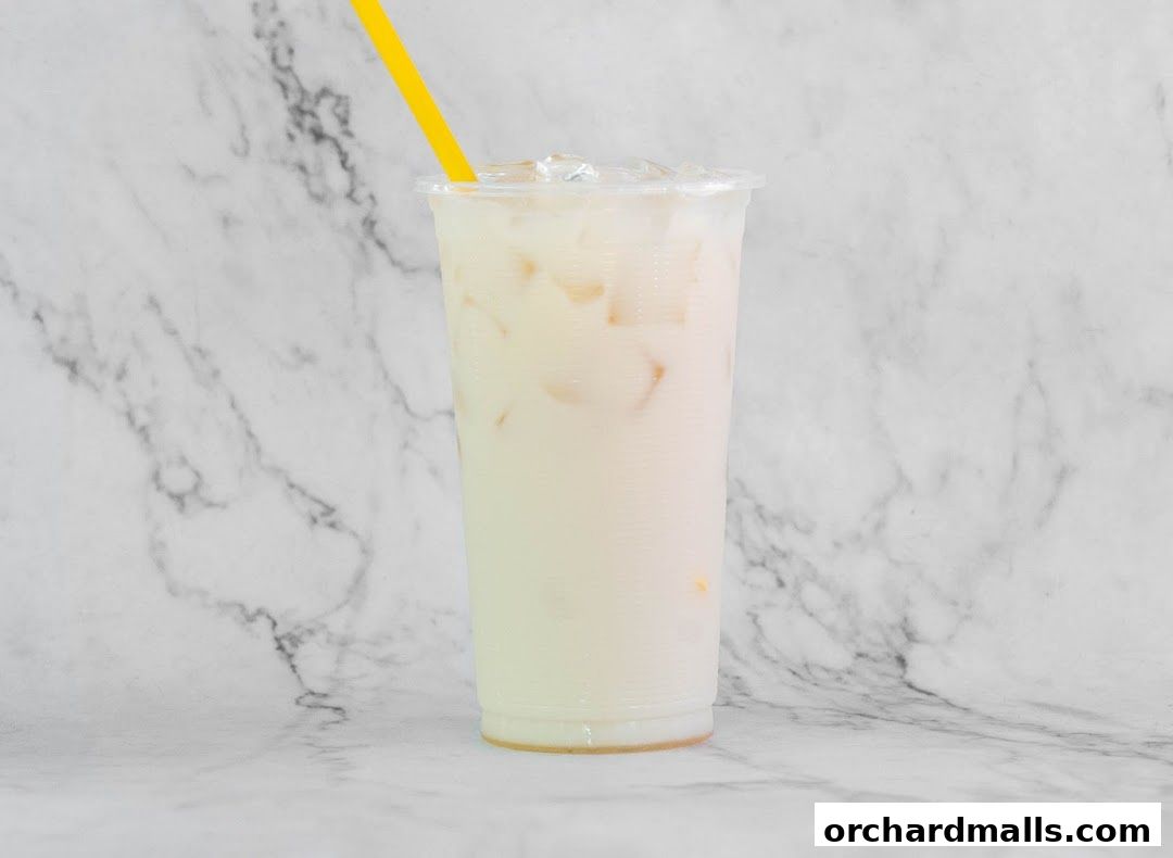 A refreshing iced milk tea with a yellow straw in a clear plastic cup.