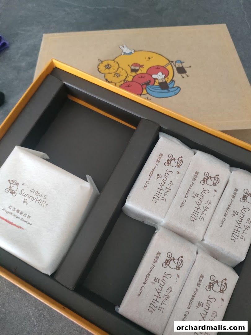 A gift box from SunnyHills Orchard containing pineapple cakes and a mooncake.