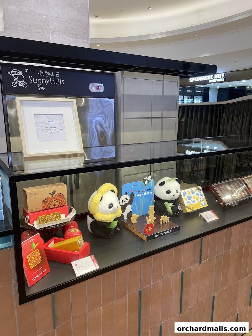 SunnyHills Orchard shop display featuring pineapple cakes, panda plush toys, and gift boxes.