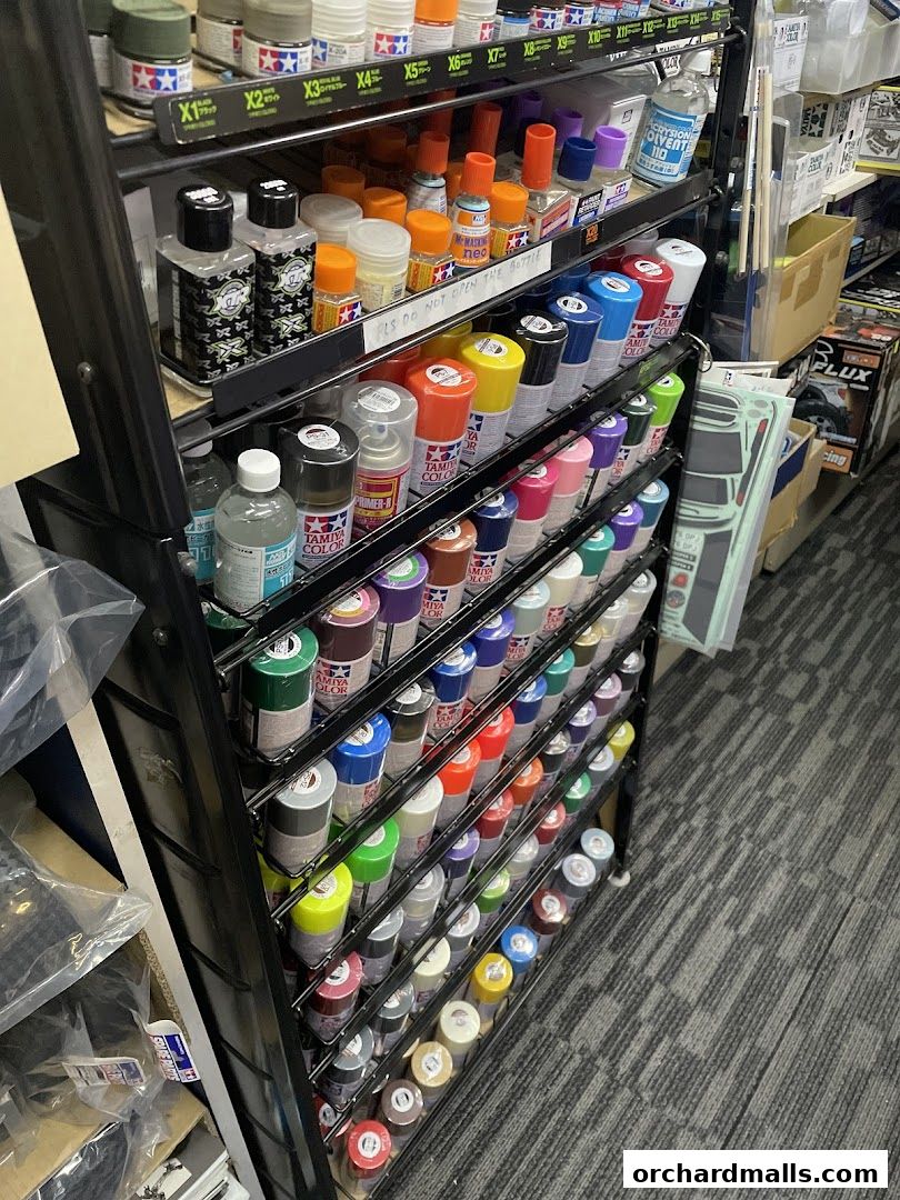 A display rack filled with various model paints and supplies, including spray cans and bottles.