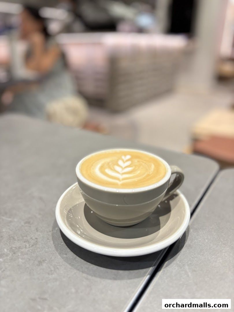 A close-up of a latte with intricate latte art on a grey table.