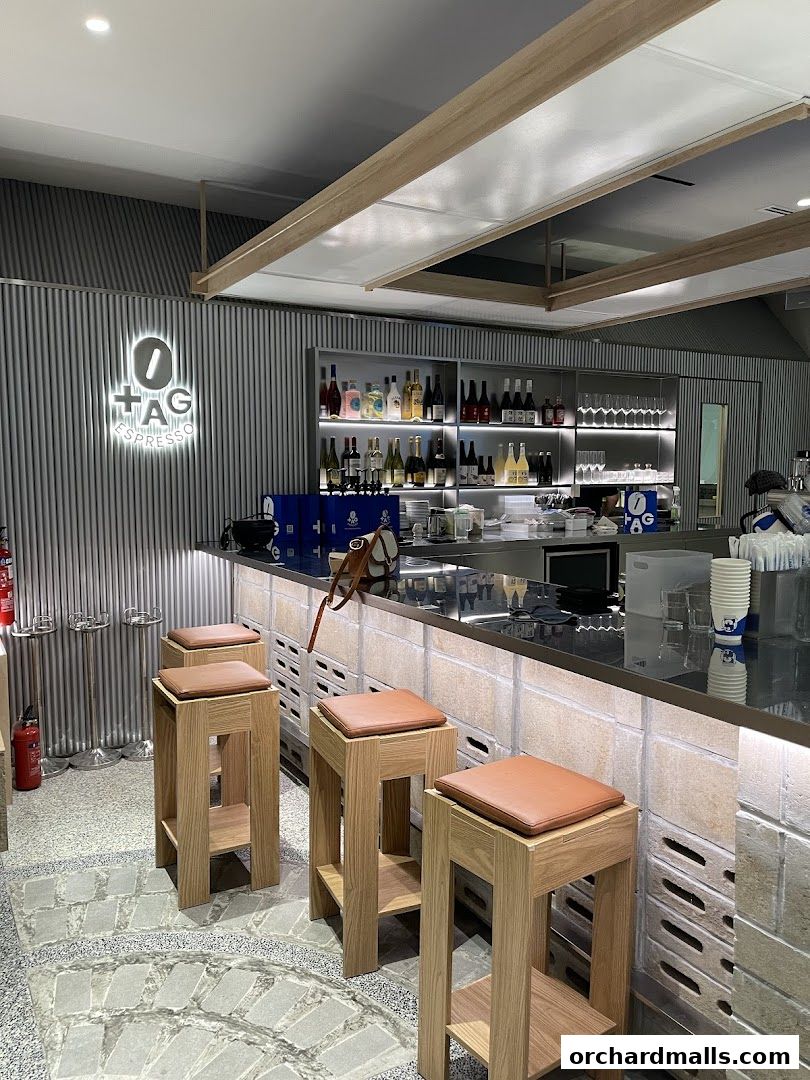 Interior of TAG Espresso cafe with bar stools, counter, and shelves stocked with bottles.