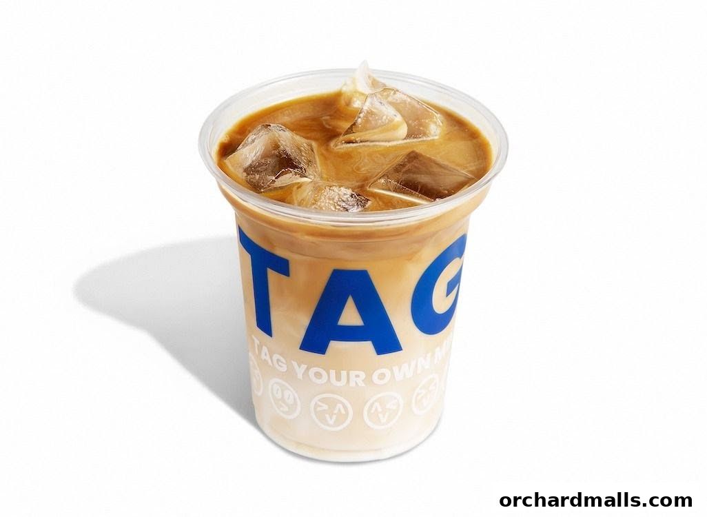 A refreshing iced coffee with milk and ice in a branded plastic cup.