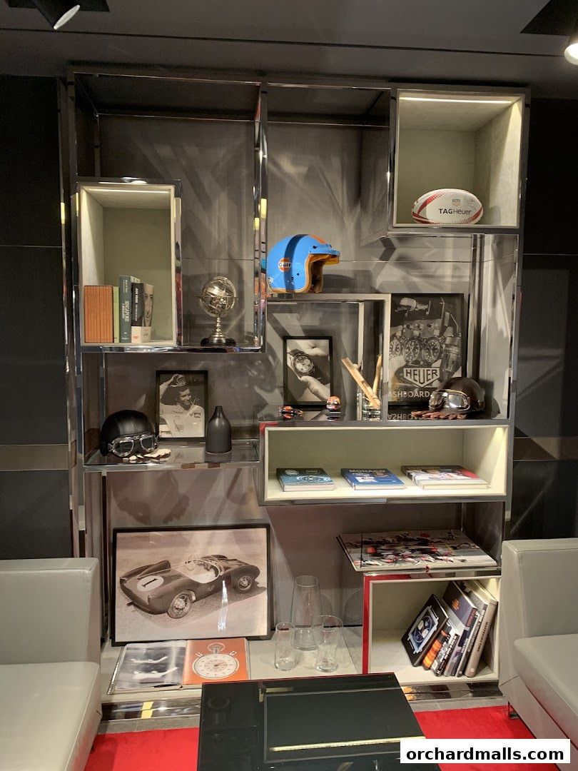 A display shelf in a TAG Heuer store featuring books, helmets, and racing memorabilia.