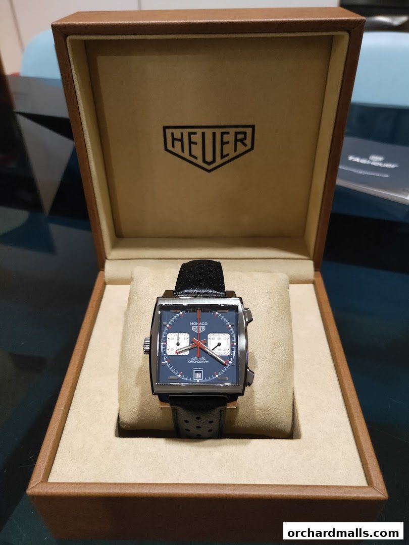 A TAG Heuer Monaco watch in its presentation box, showcasing its blue dial and black leather strap.