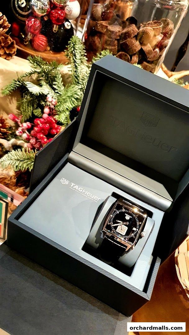 A TAG Heuer watch in its box, with festive holiday decorations in the background.