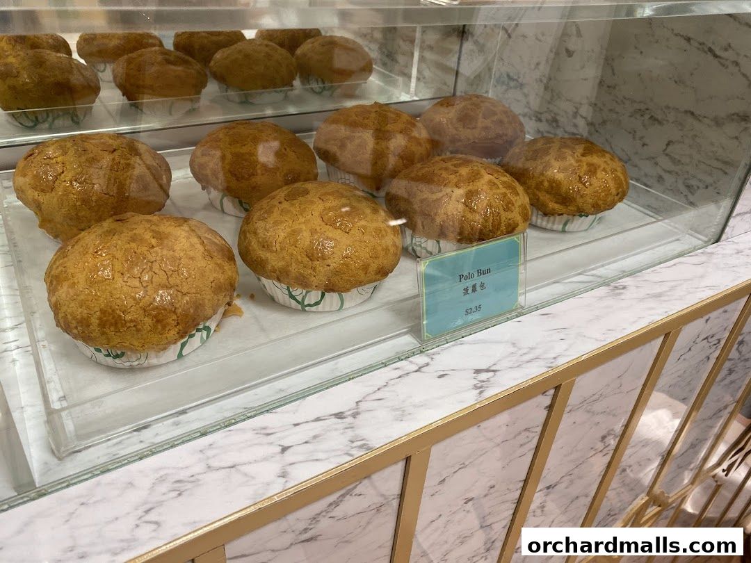 Golden brown polo buns displayed in a bakery case with a price tag.