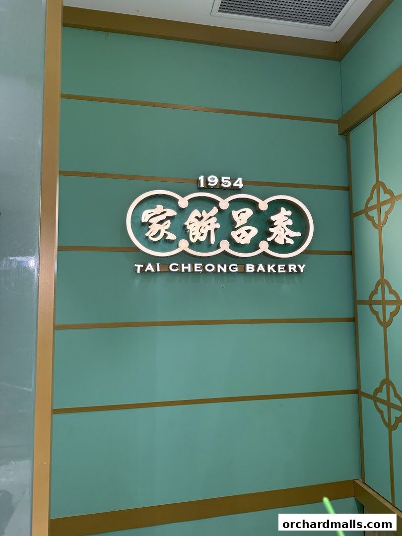 The Tai Cheong Bakery logo is displayed on a teal wall with gold accents.