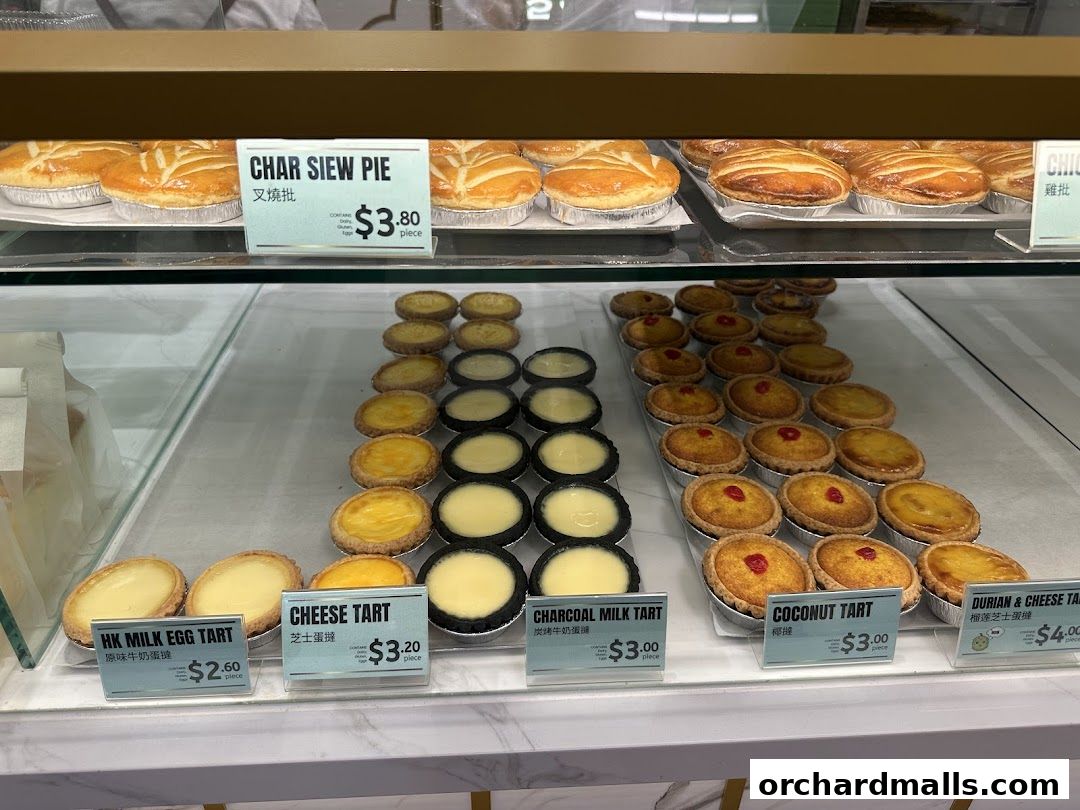 A display case filled with various freshly baked tarts and pies from Tai Cheong Bakery.