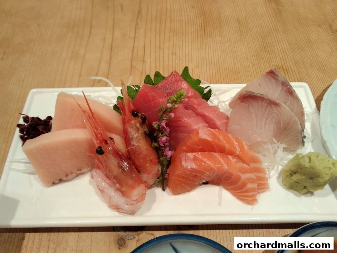 A platter of fresh sashimi, including tuna, salmon, and white fish, with shrimp and wasabi.