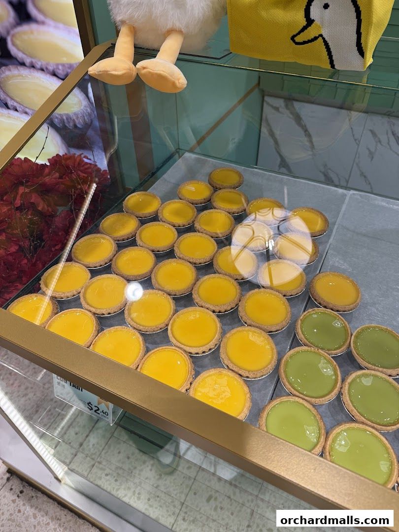 A display case filled with freshly baked egg tarts and matcha tarts.