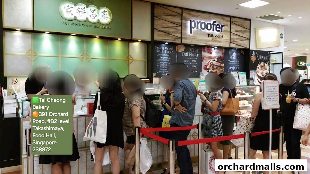 A queue of customers outside Tai Cheong Bakery and Proofer Patisserie in a food hall.