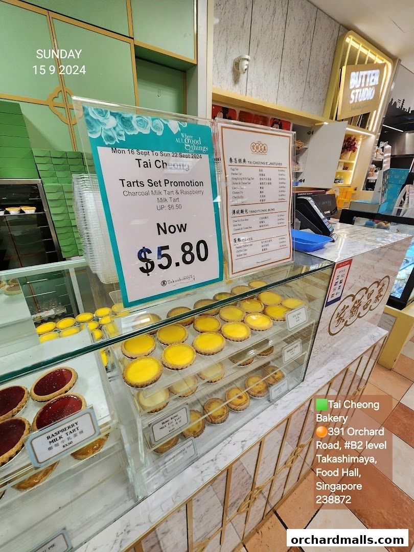 A display case filled with tarts and a promotion sign for Tai Cheong Bakery.