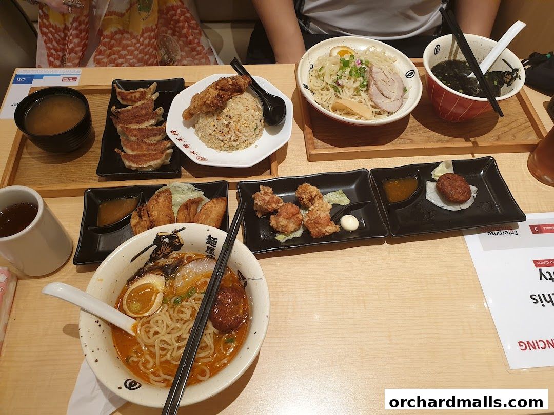 A table laden with various Japanese dishes including ramen, fried rice, gyoza, and fried chicken.