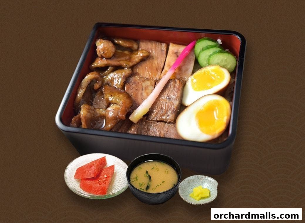 A bento box with meat, egg, cucumber, pickled ginger, miso soup, and fruit.