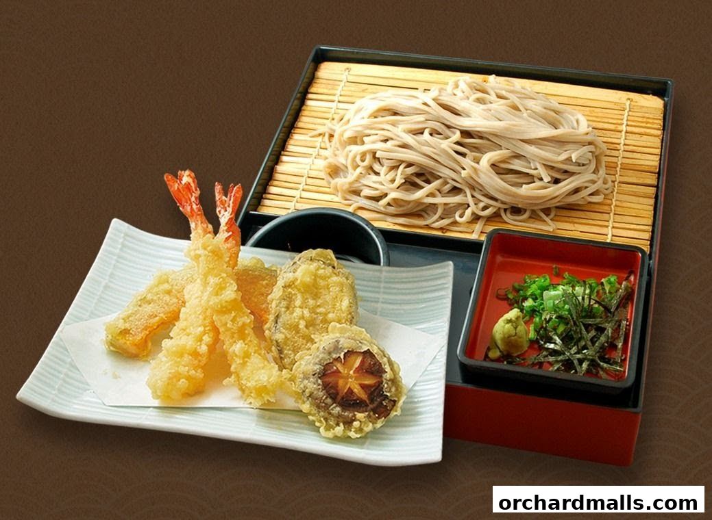 A delicious serving of tempura and soba noodles with dipping sauce and garnishes.