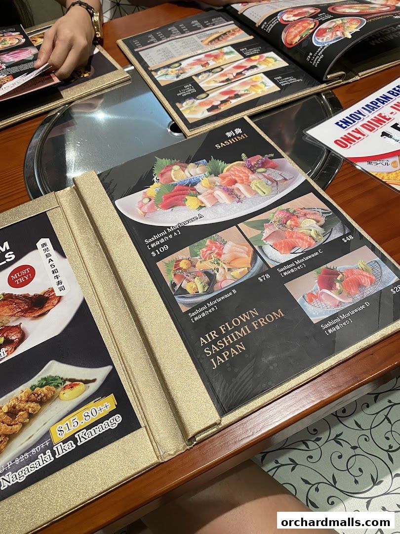 A close-up of a Japanese restaurant menu featuring sashimi and other dishes.