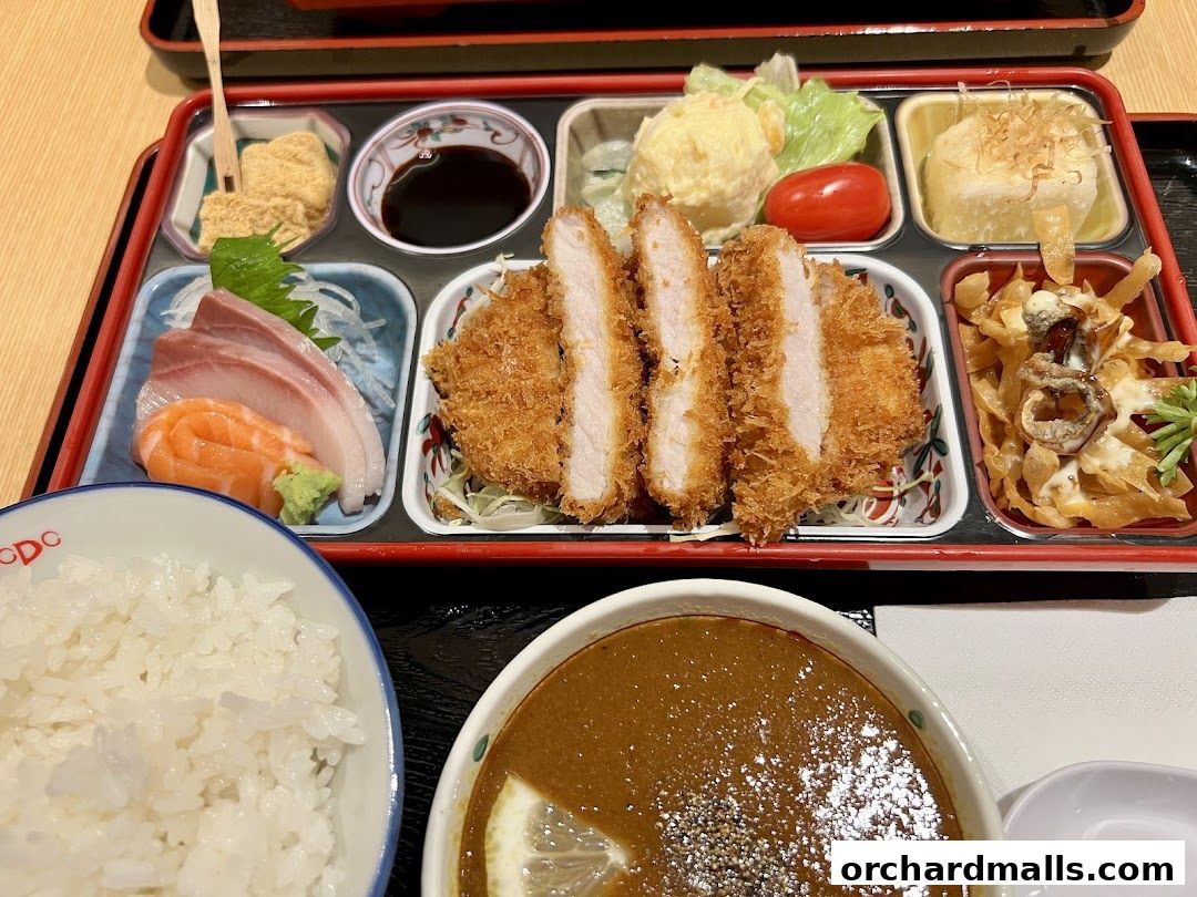 A bento box with katsu, sashimi, rice, and soup, presented on a tray.