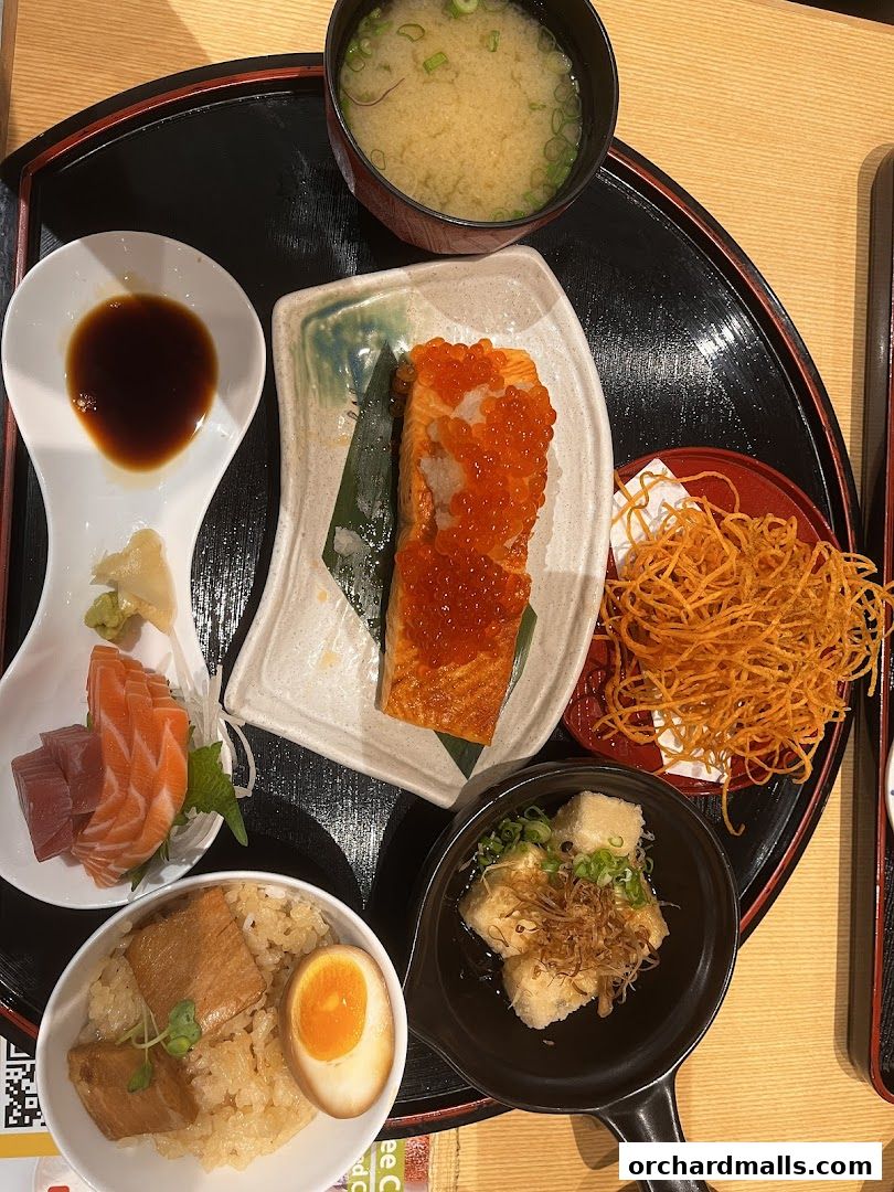 A Japanese meal set featuring salmon, tuna sashimi, rice, miso soup, and fried tofu.