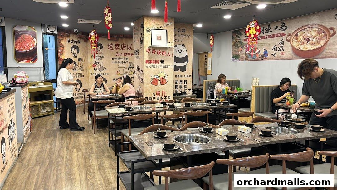 Interior of a restaurant with tables set for hot pot, featuring decorative wall art and patrons dining.