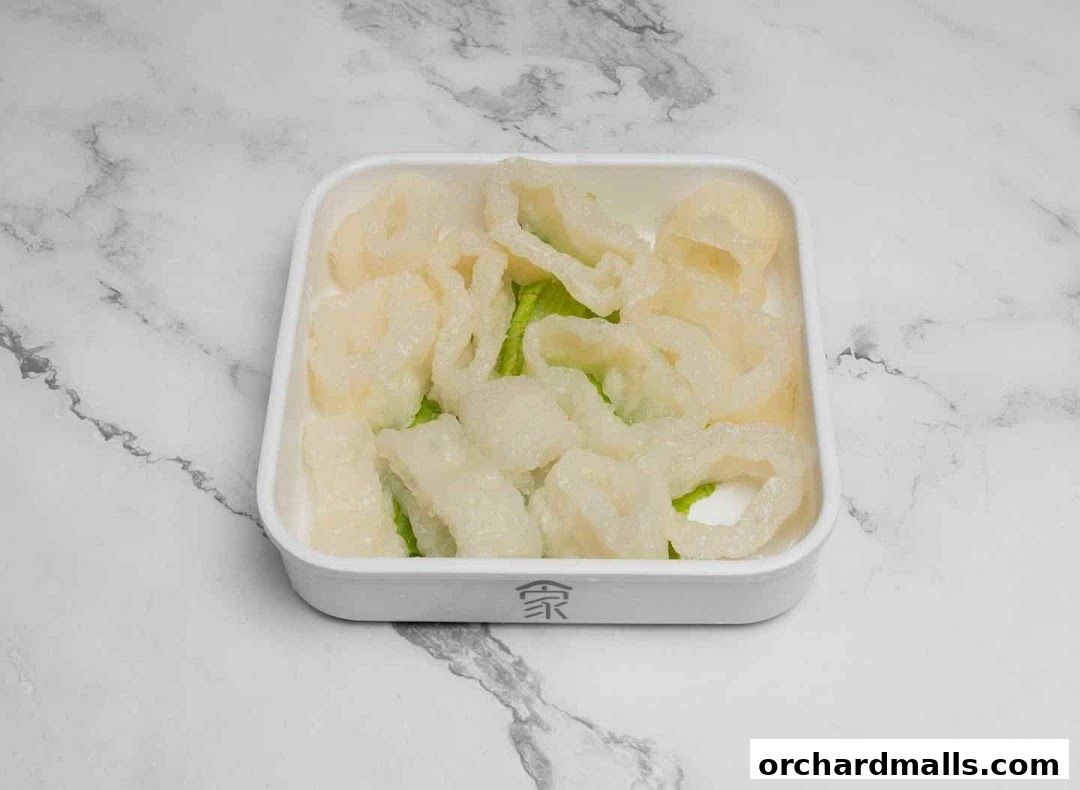 A white bowl filled with white, textured food items and green lettuce on a marble background.