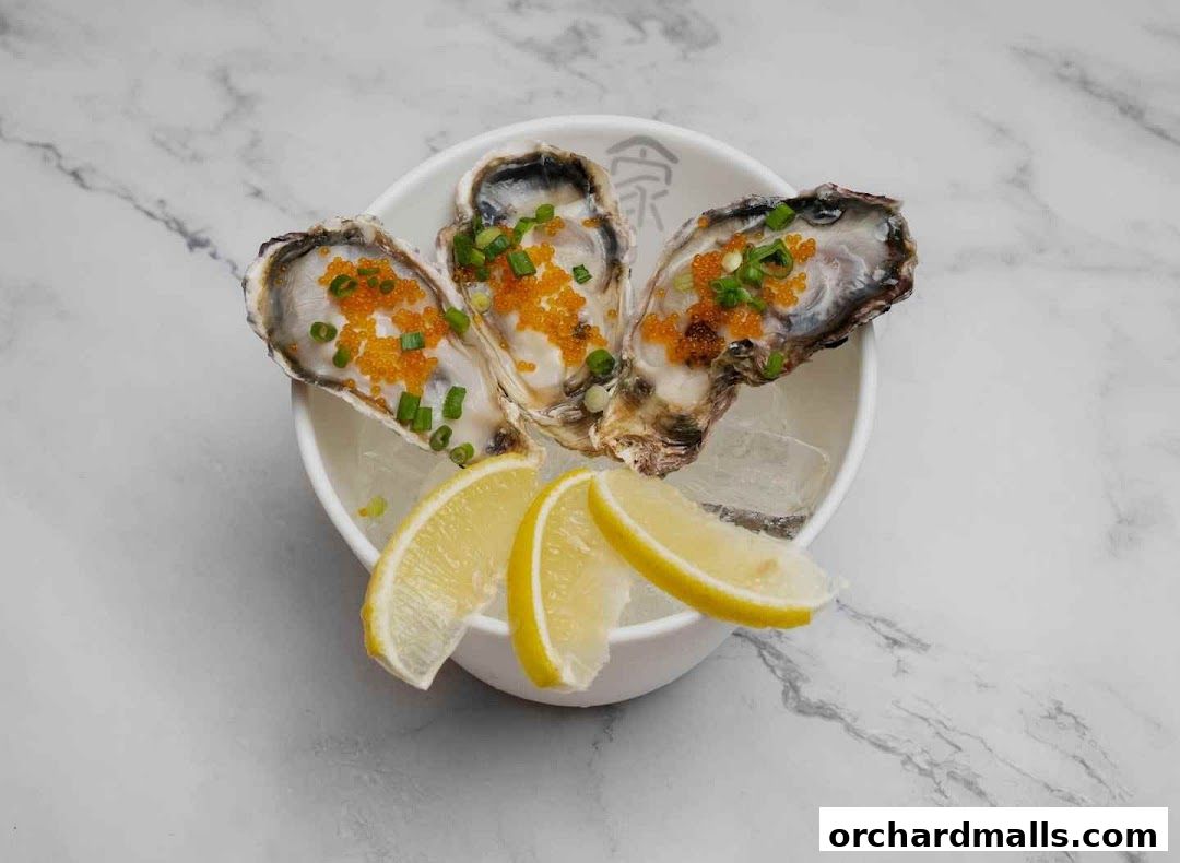 Three fresh oysters topped with roe and chives, served with lemon slices on ice.