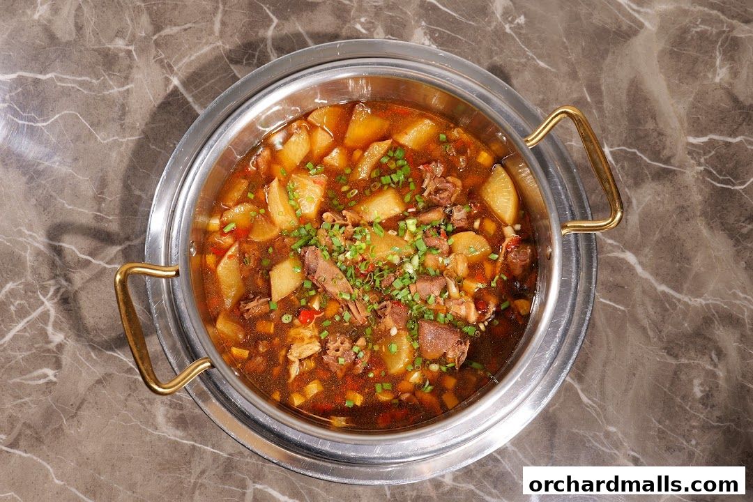 A close-up overhead shot of a hearty stew with meat and vegetables in a metal pot.