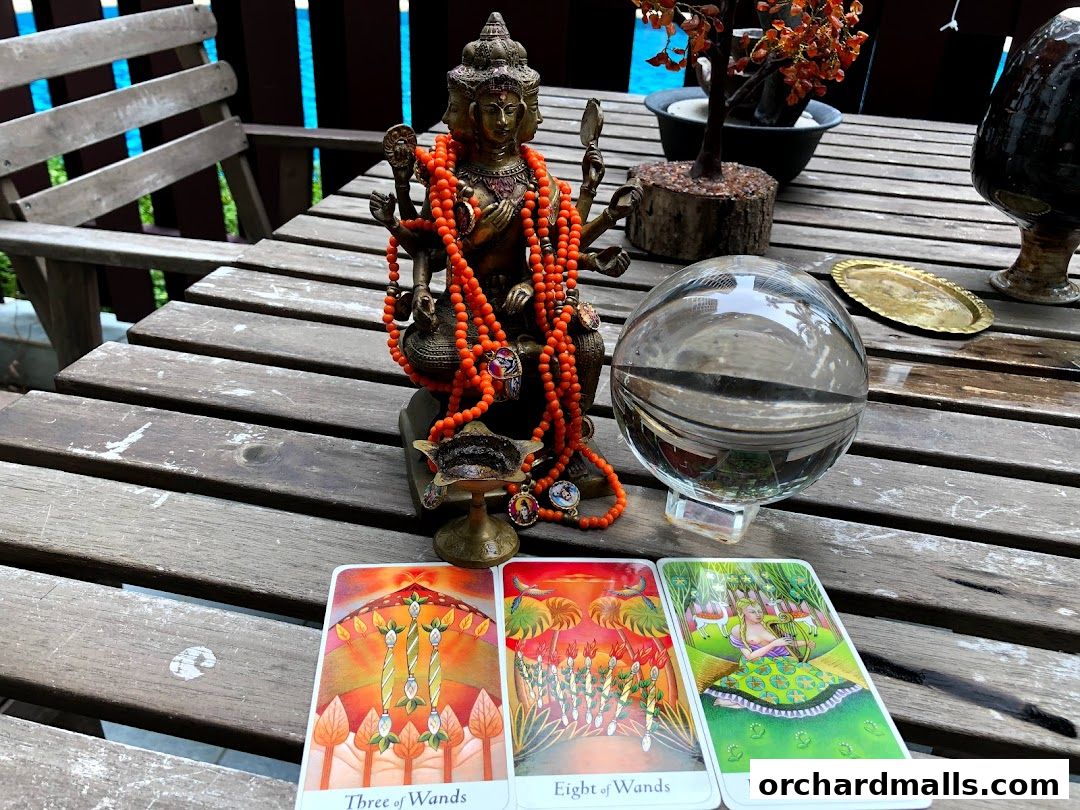 Tarot cards, a crystal ball, and a statue are arranged on a wooden table.
