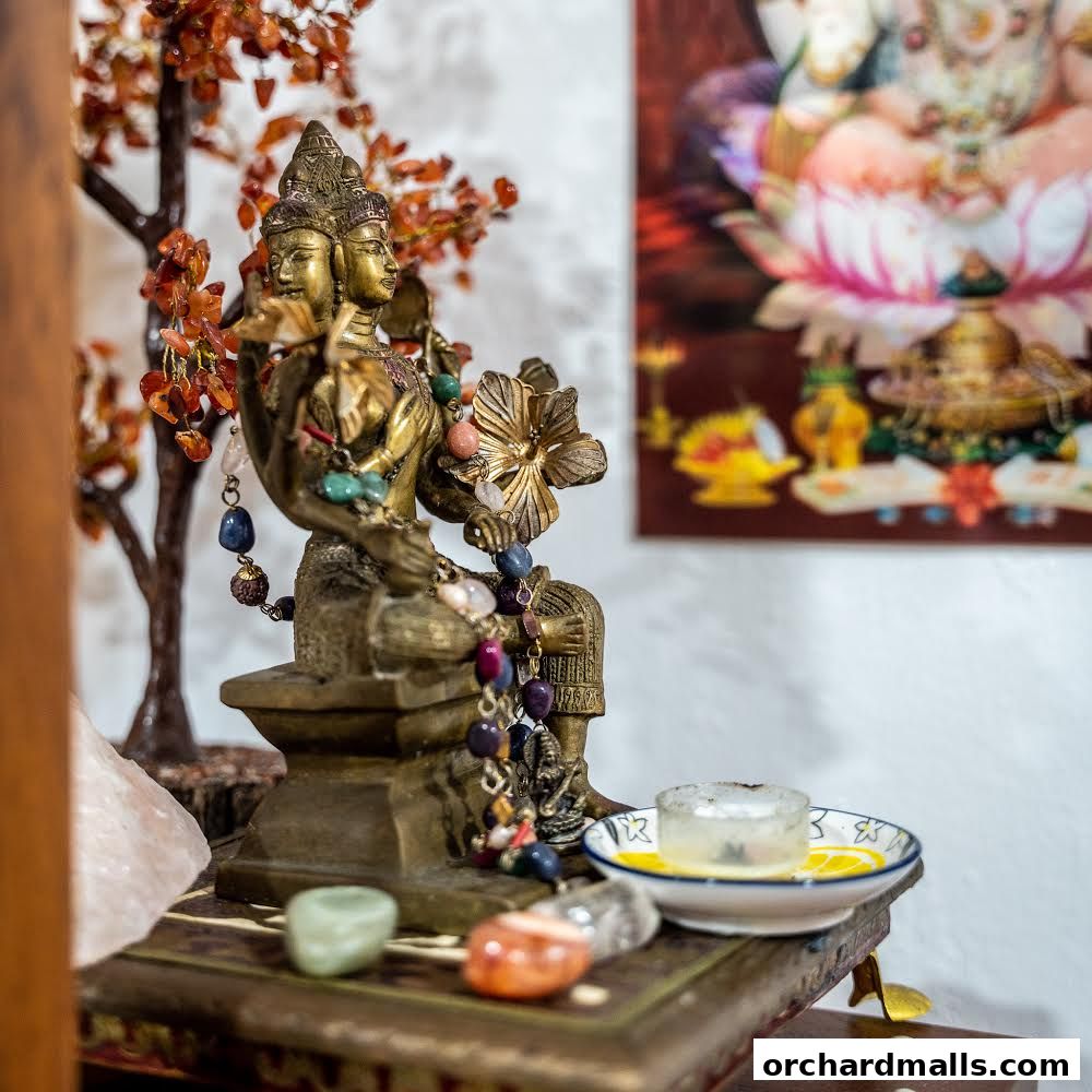 A brass statue of a multi-faced deity adorned with prayer beads and crystals.