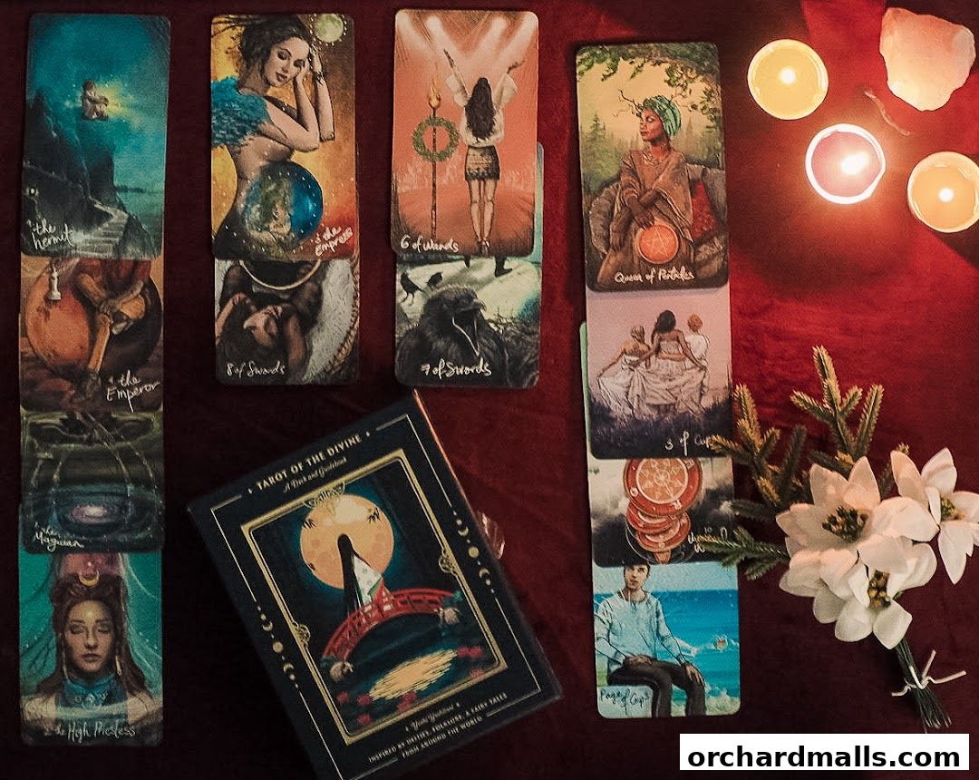 Tarot cards and a guidebook are laid out with candles and flowers on a red cloth.
