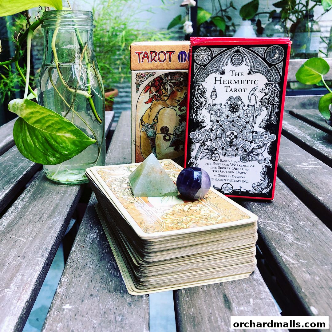 A stack of tarot cards with crystals and plants on a wooden table.