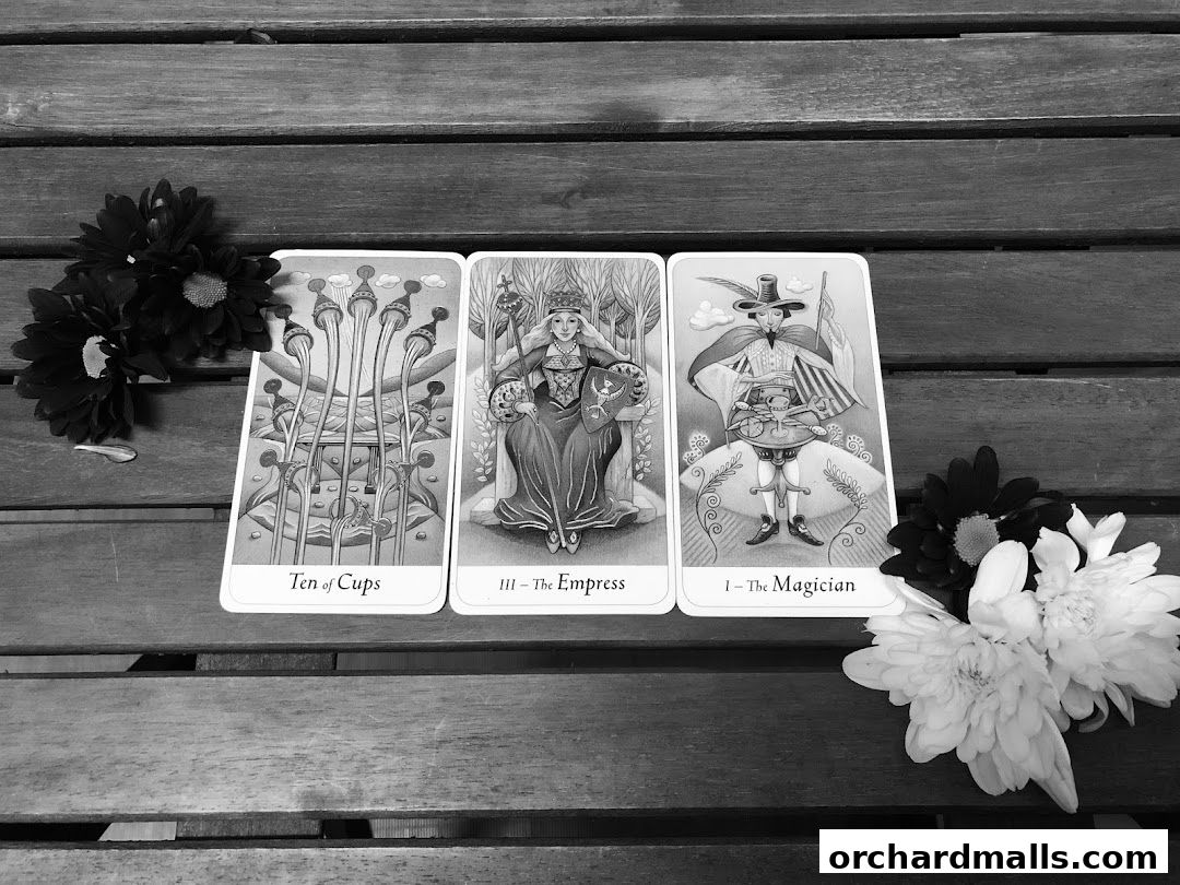 Three tarot cards, Ten of Cups, The Empress, and The Magician, with flowers.