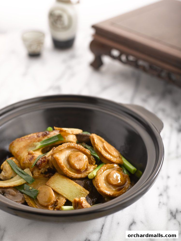 A close-up of a delicious abalone dish served in a black ceramic pot.