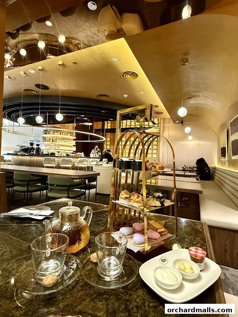 A luxurious tea set with pastries and tea on a marble table in an elegant cafe.