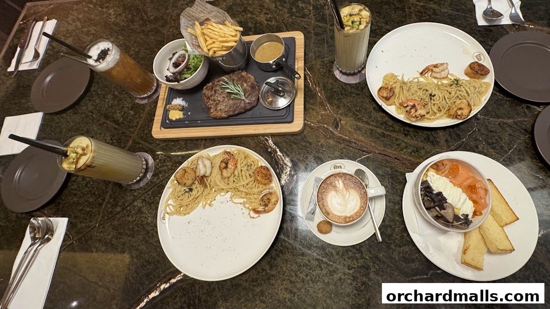 A table laden with various dishes including steak, pasta, salmon, and drinks.