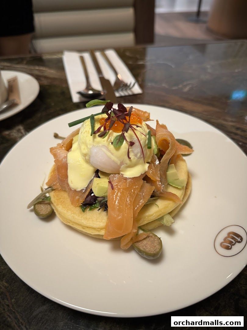 A gourmet dish featuring smoked salmon, poached egg, avocado, and capers on a pancake.